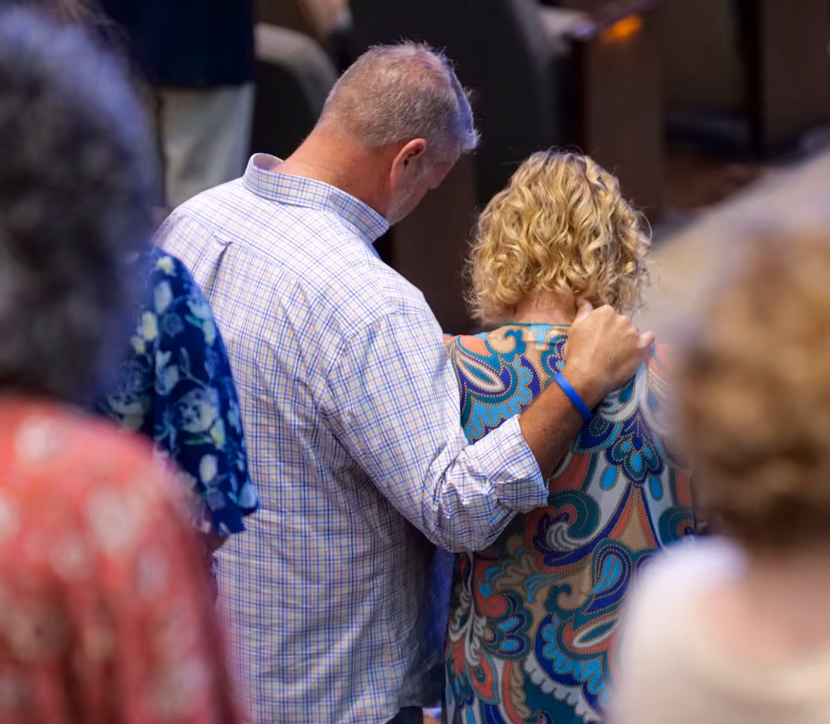 Older man with hand on back of woman with curly blonde hair