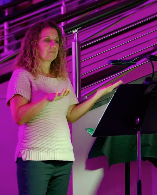 Woman presenting with expressive gestures under vibrant purple lighting