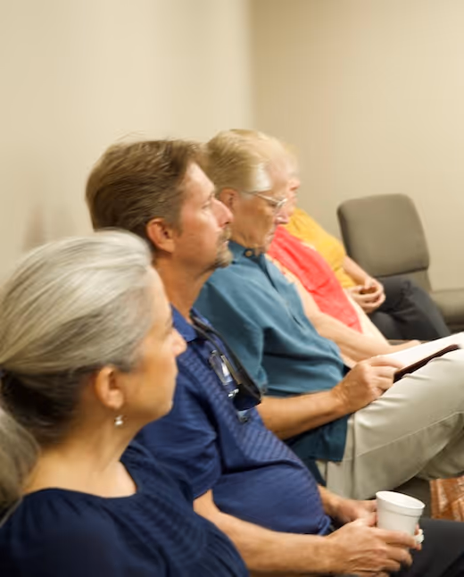 Diverse group of older people sitting together, reading and holding a cup