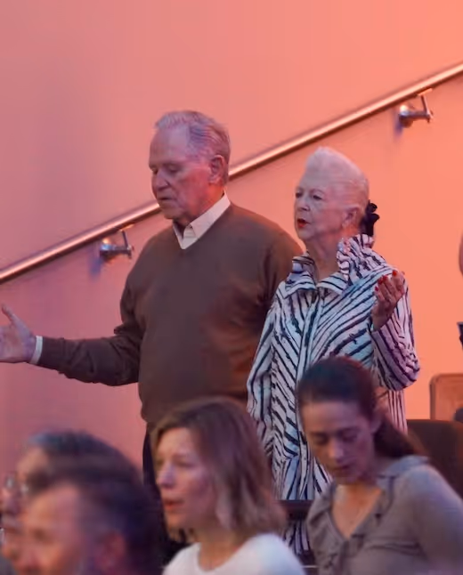 Elderly couple standing together on stairs with pink background lighting