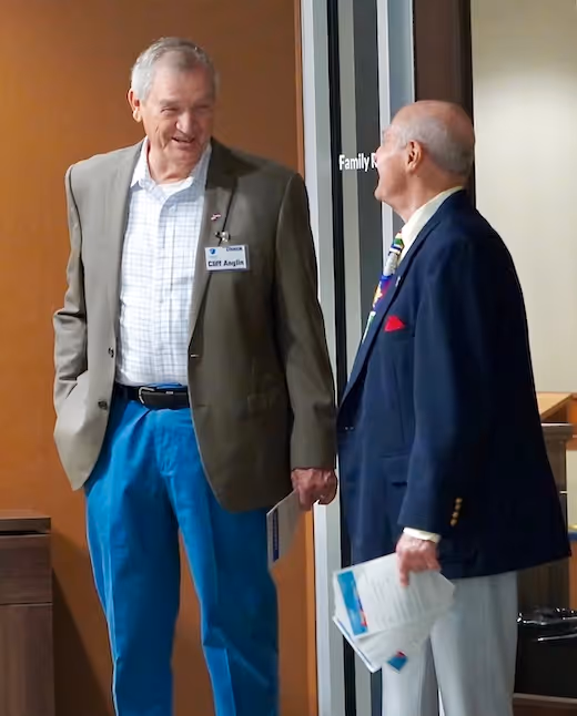 Two senior men in business attire chatting near a door