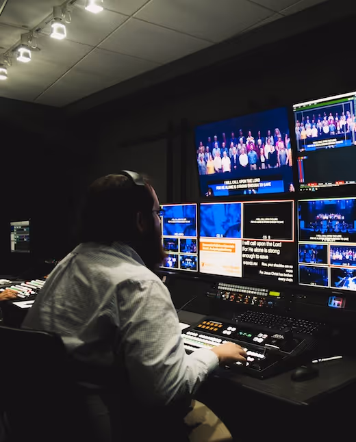 Television production control room with multiple screens and a technician