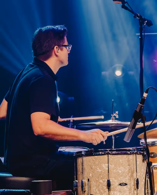 Drummer playing on stage with blue stage lights and microphone