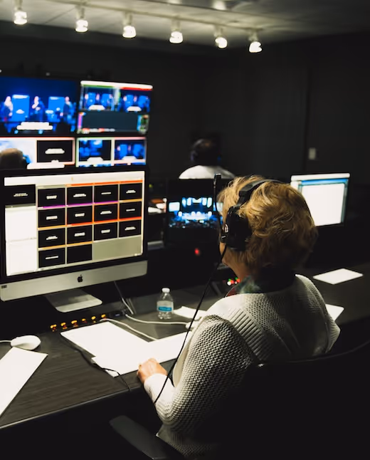 TV control room operator working at monitors with headset on