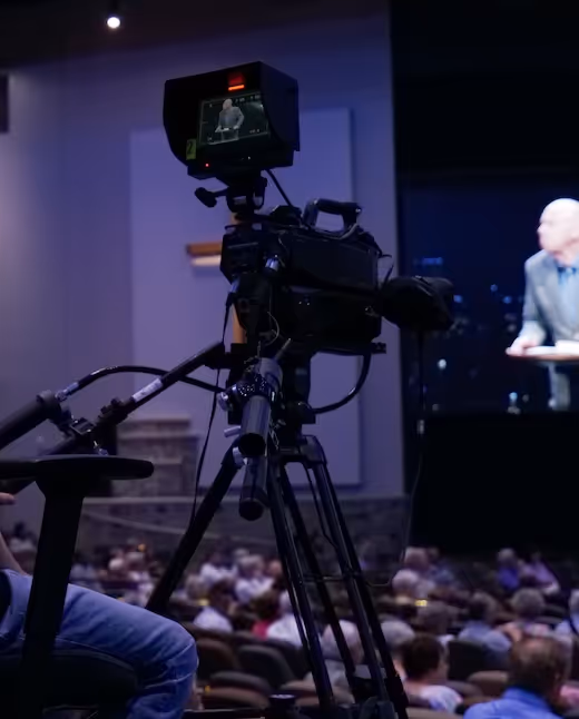 Professional video camera recording a speaker at a crowded conference event