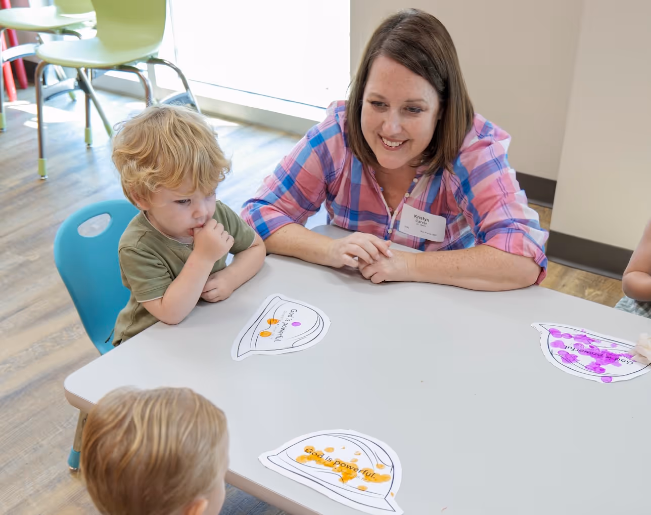 Teacher and young child working together at a table with learning materials