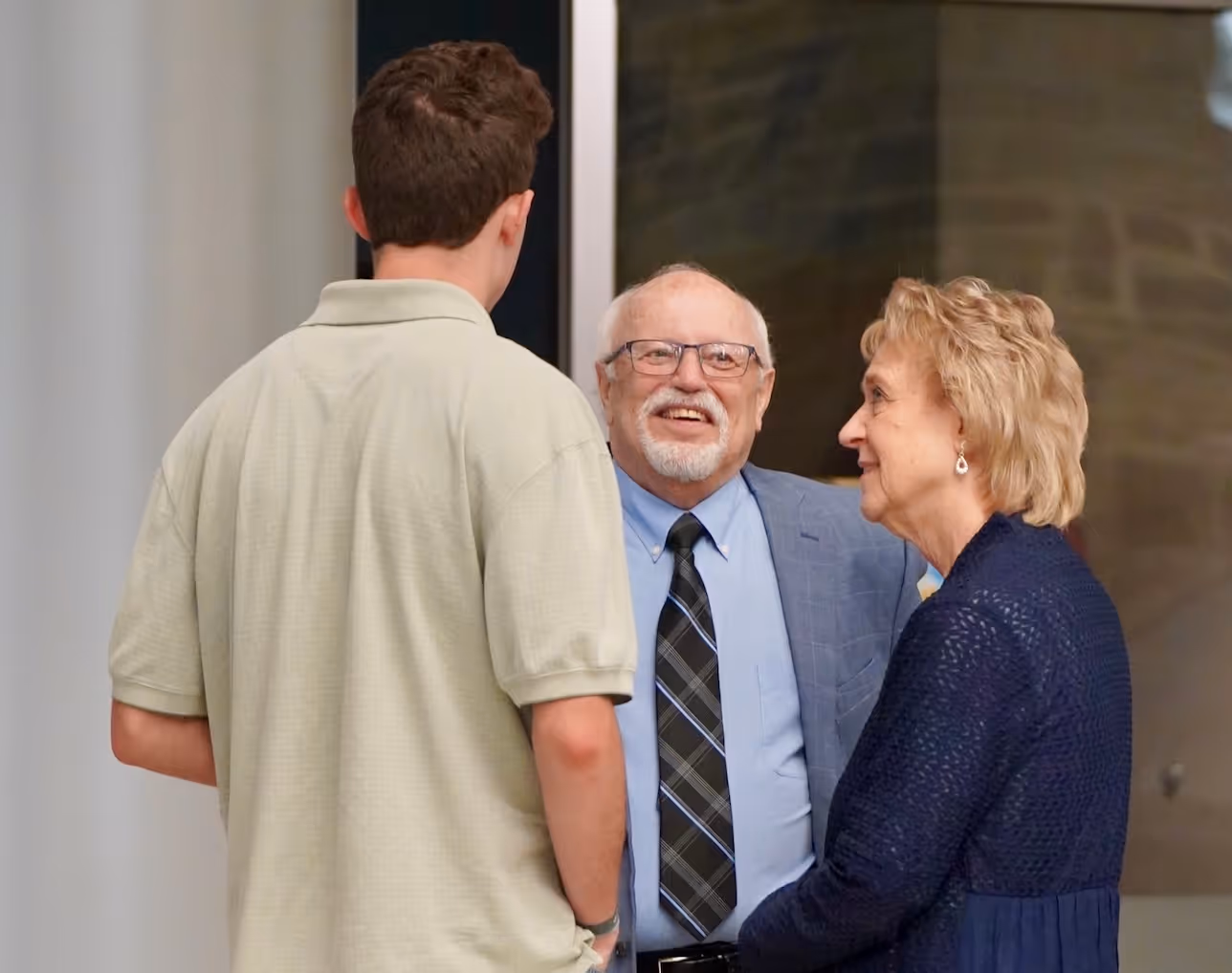 Three people conversing warmly in an office or professional setting
