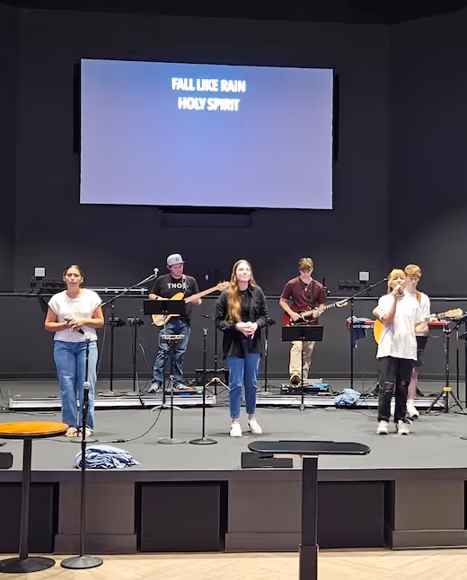 Worship band on stage with "Fall Like Rain" displayed on screen