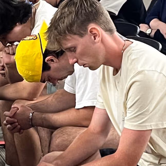 Athletes in white shirts sitting together, heads down in intense moment