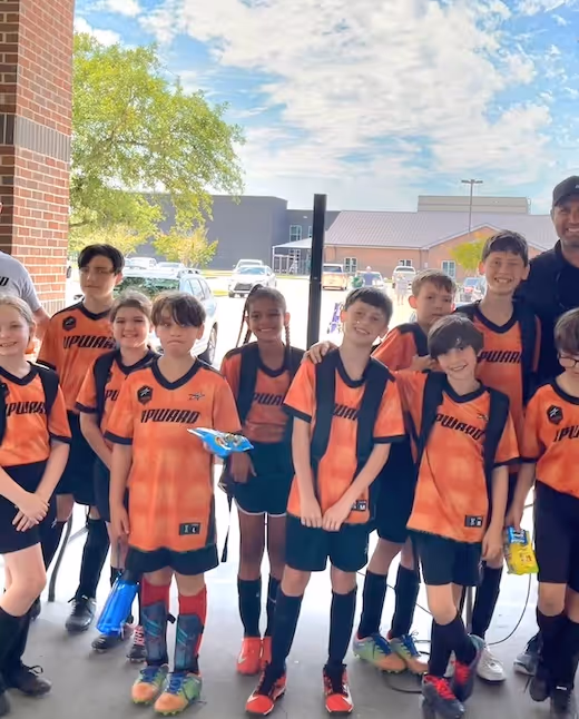 Youth soccer team in orange jerseys posing together before a match