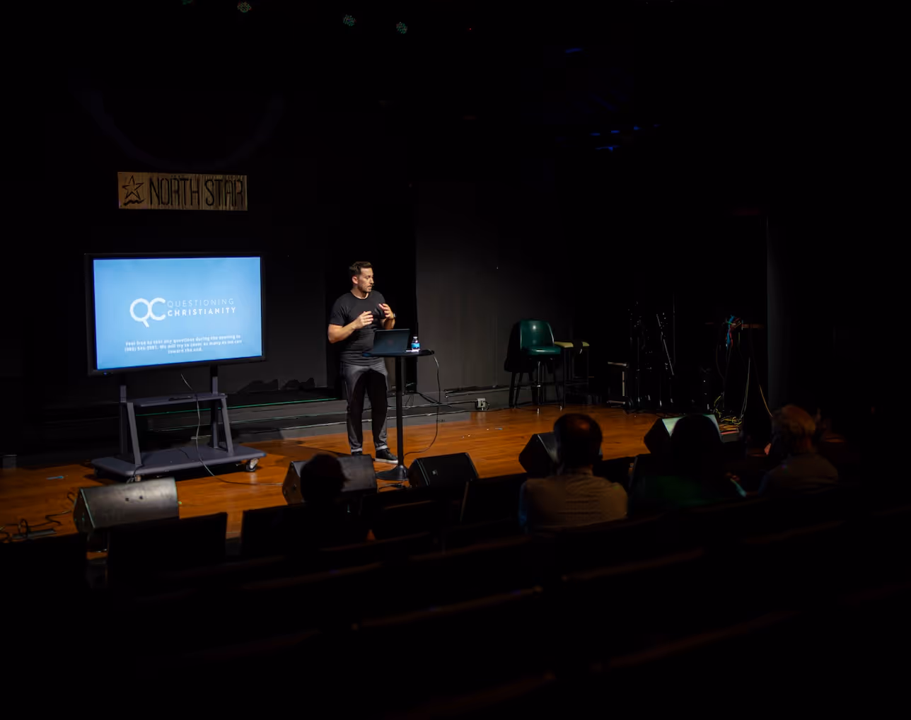 Speaker presenting QC Christianity talk on stage at North Star venue