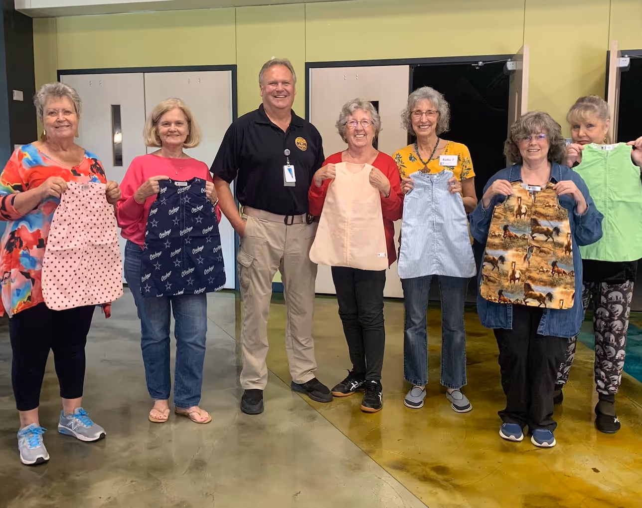 Group of seniors holding handmade aprons at community craft workshop