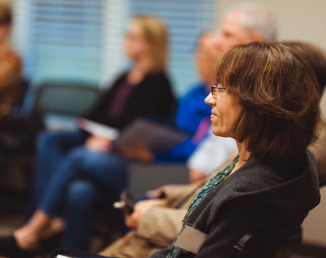 Woman with glasses attentively listening during a meeting or conference
