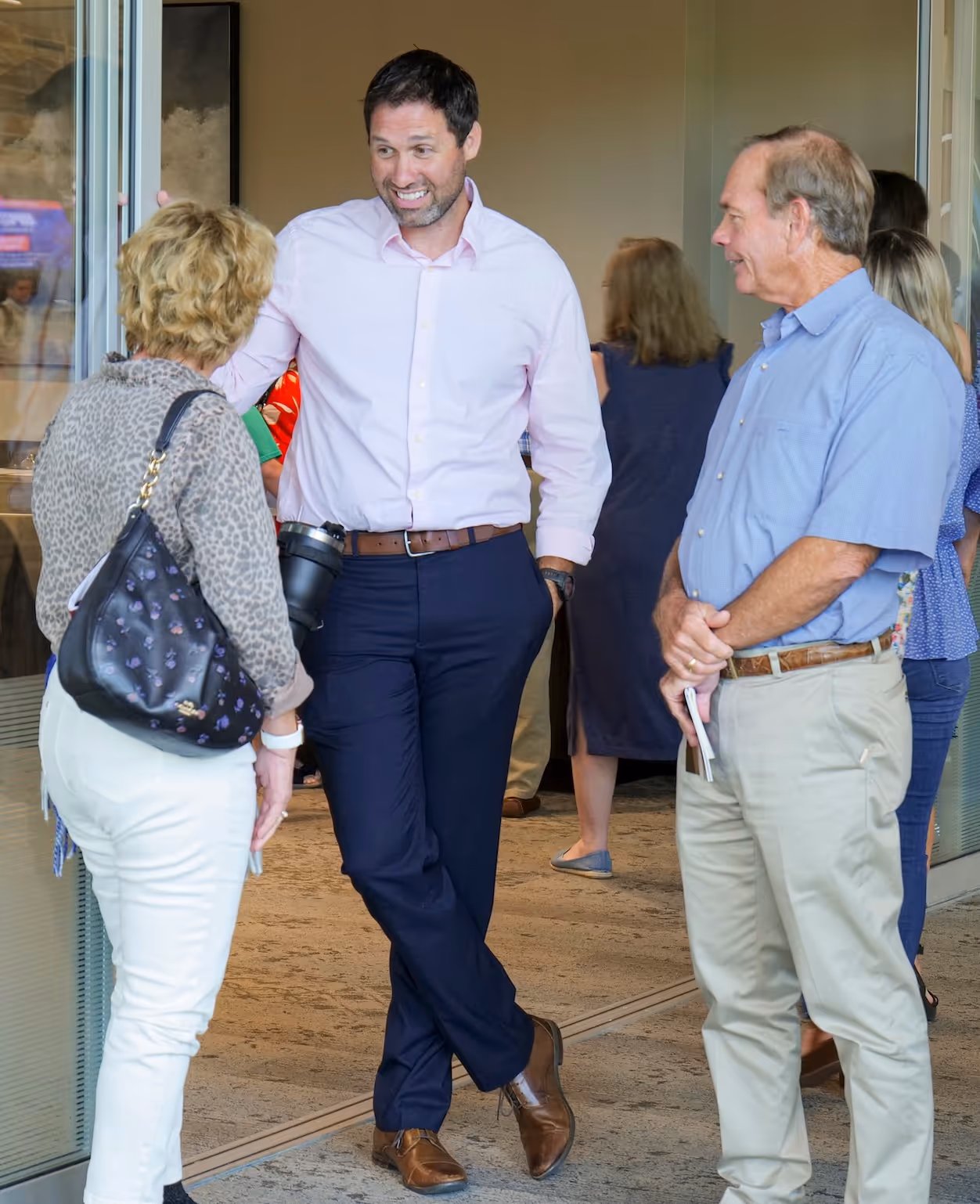 Professional colleagues conversing near glass doors in business casual attire