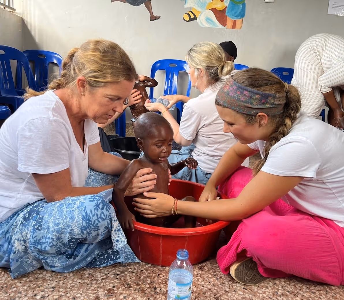Volunteers caring for malnourished child in red basin during humanitarian aid mission