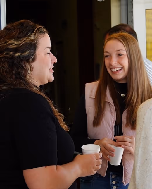 Two women laughing and enjoying coffee together in casual setting