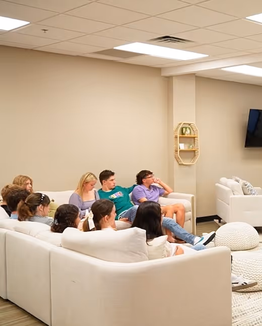 Group of people relaxing and sitting together on white couches in a room
