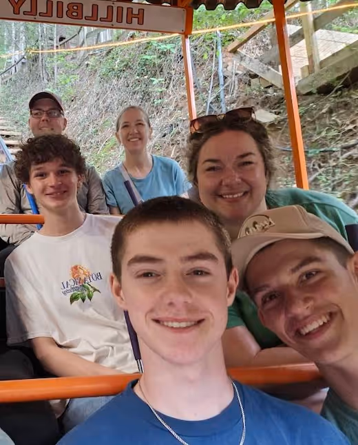 Group of people smiling together on a hillbilly ride in forest setting