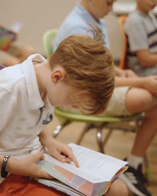 Young student concentrating on reading a book in classroom