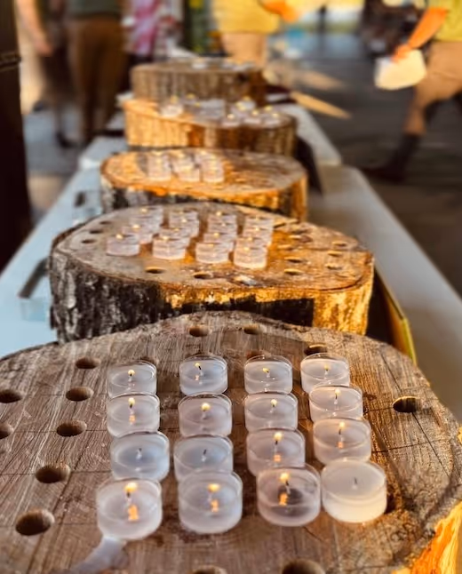 Wooden logs with lit tea light candles arranged in rows
