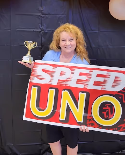 Singles ministry champion holding Speed UNO trophy and game sign