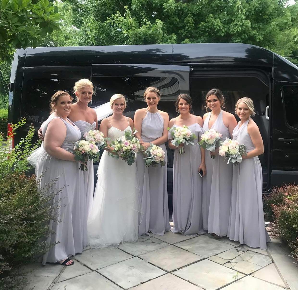 Bride and bridesmaids posing in front of a Metro Livery wedding shuttle in Lebanon TN