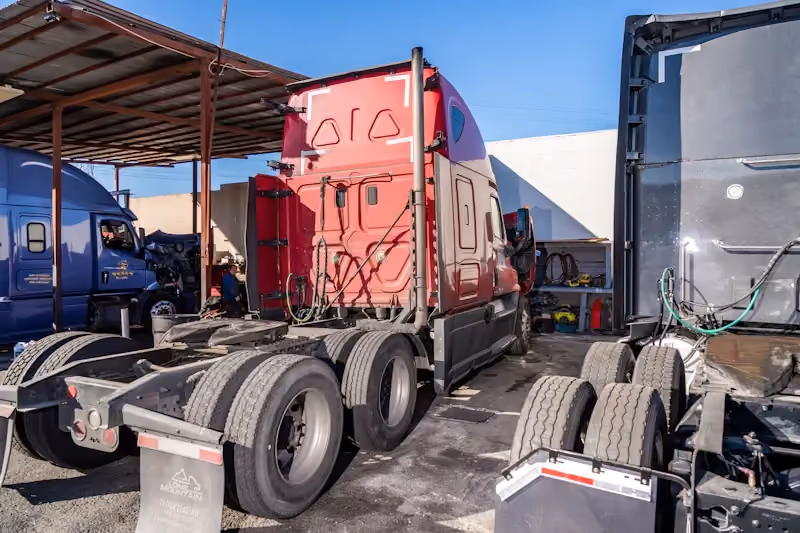 Heavy-duty repair facility with multiple semi-trucks staged in a service yard for maintenance and fleet repairs.