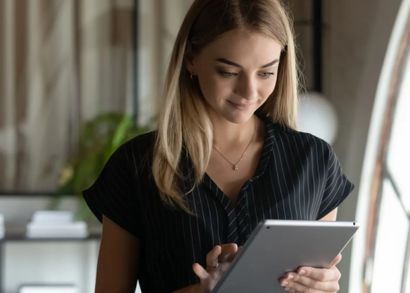 Professional woman using a digital tablet in a modern office environment.