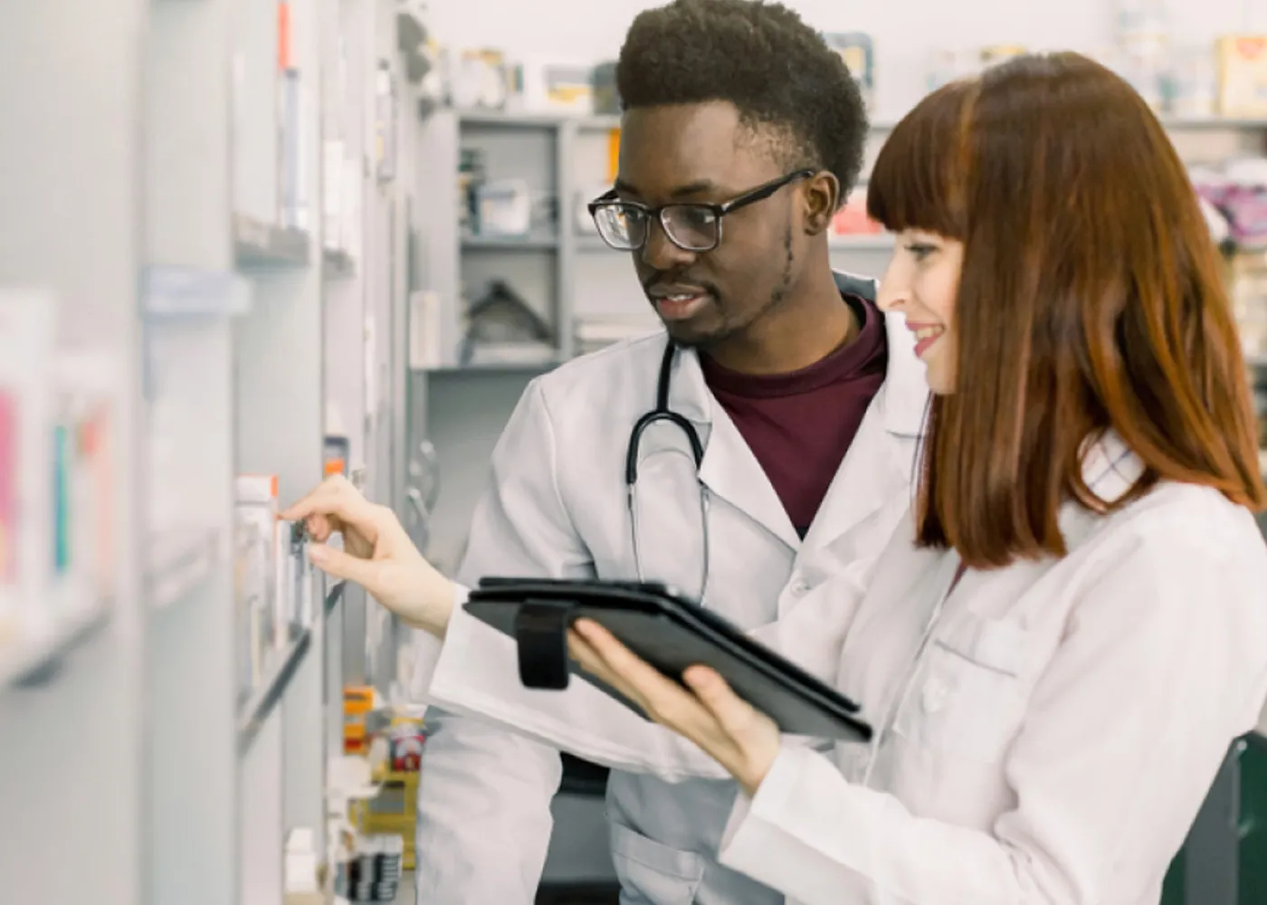 Two healthcare professionals reviewing medications and patient data using a digital tablet