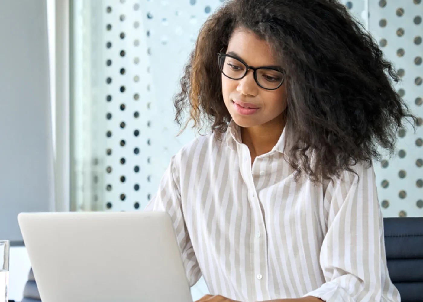 Professional woman working on a laptop in a modern office, analyzing business data