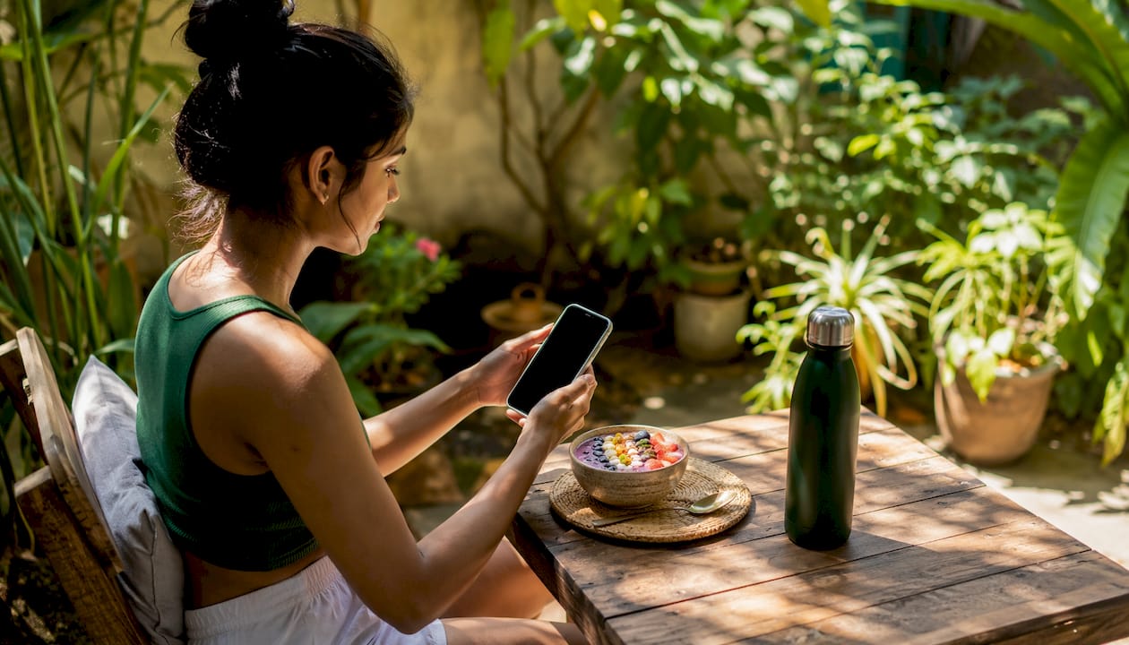 Woman using weight loss coaching app at kitchen island