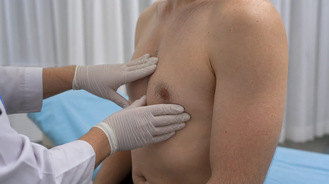 Hands conducting male breast exam