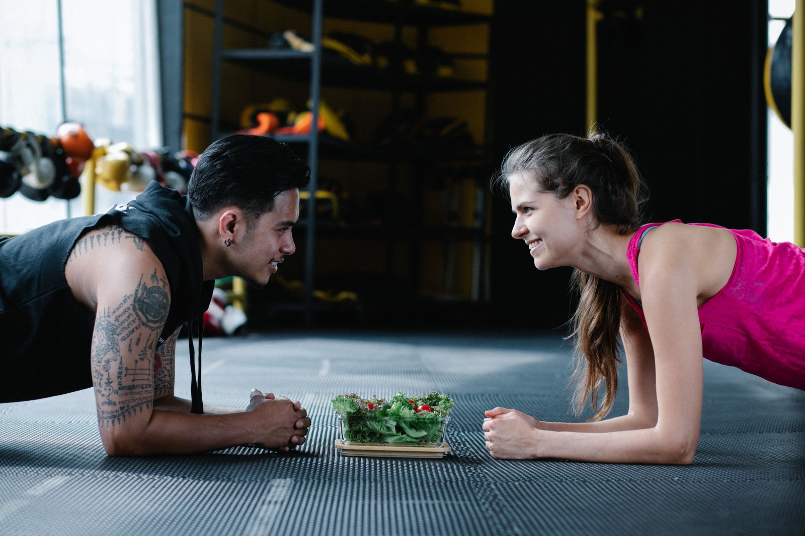 Two people planking in a gym beside a fresh salad — combining activity and nutrition with FitRx