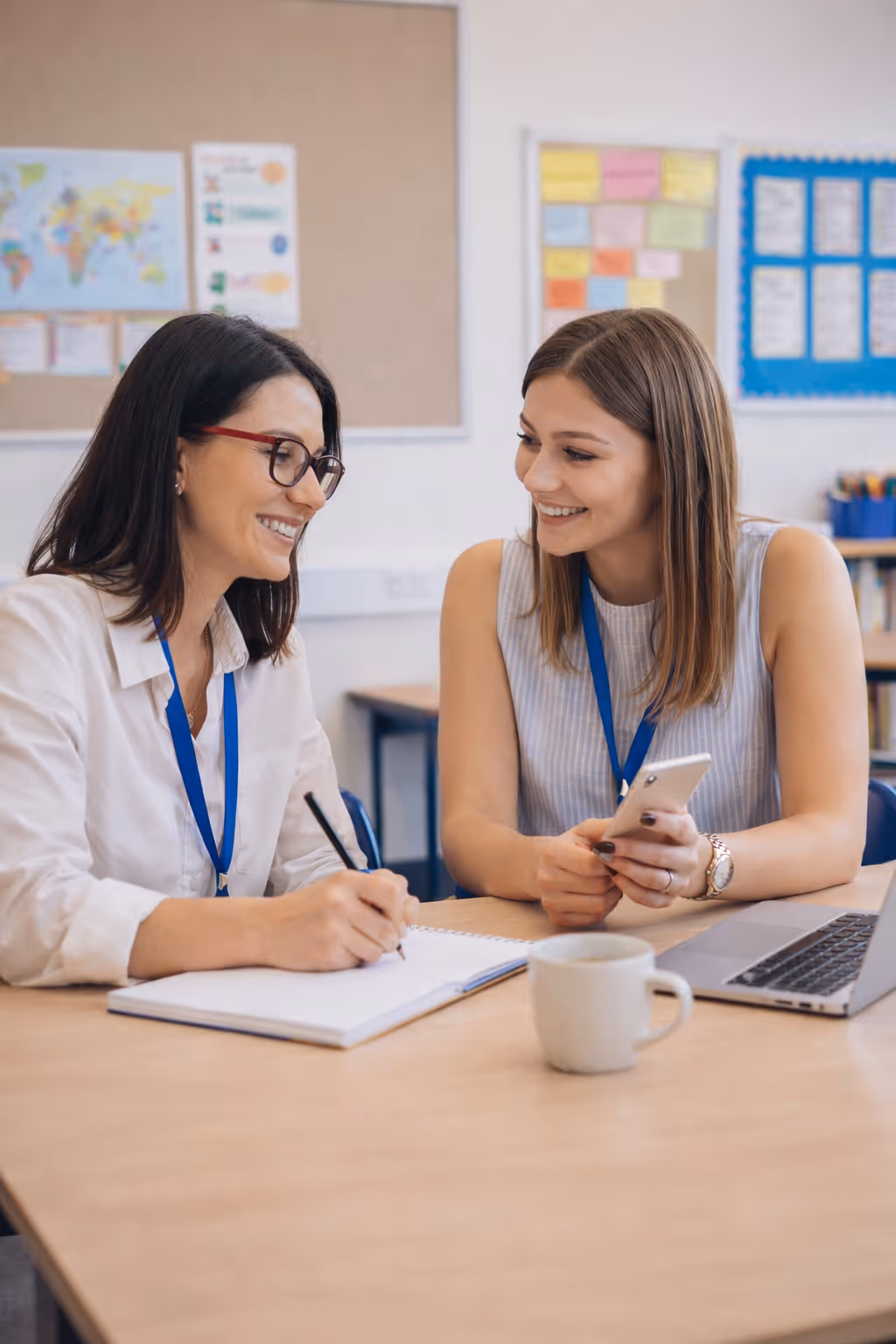 A teacher assists a group of diverse students using tablets in a bright classroom.