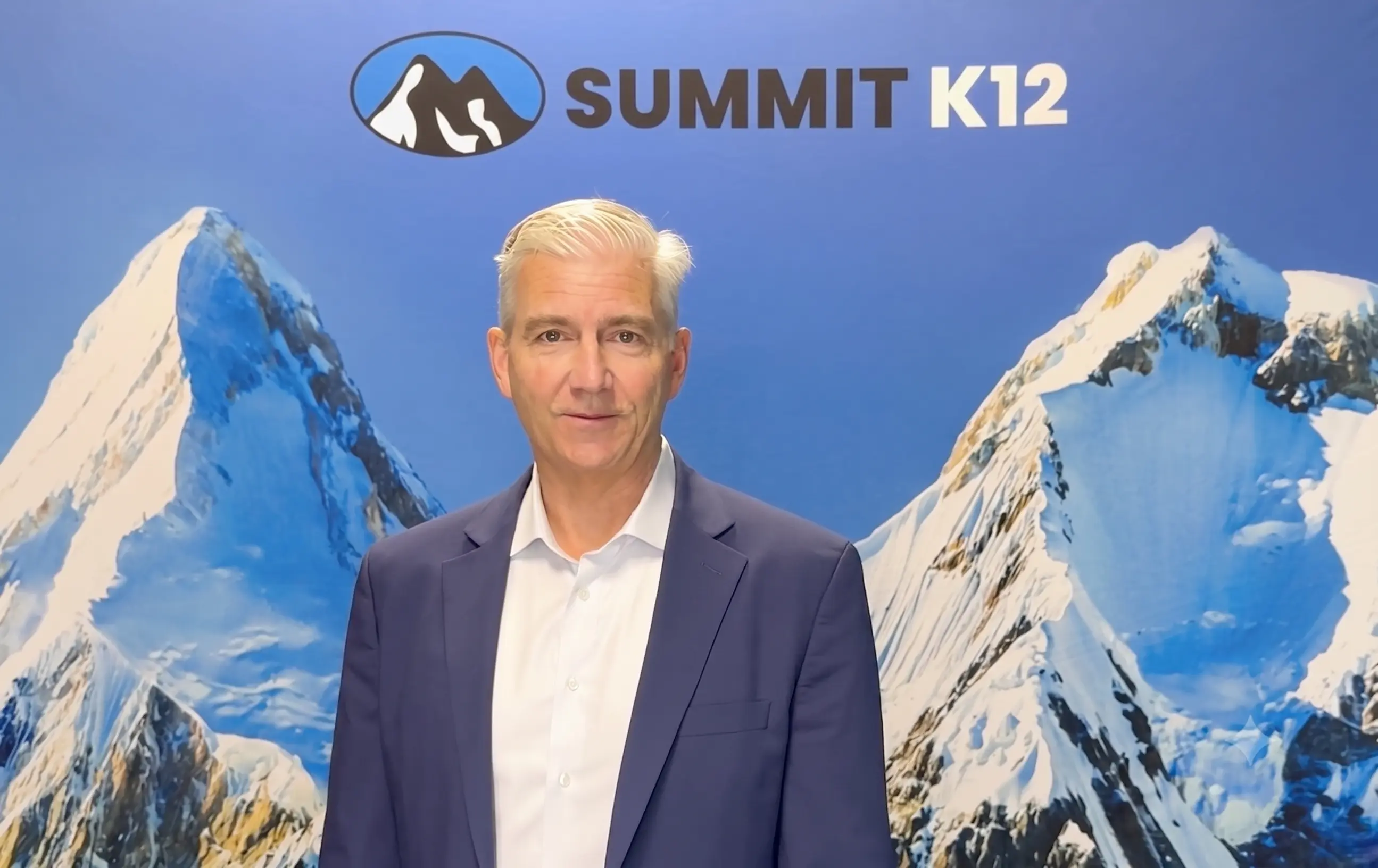 Summit K12 logo with black and white mountain peaks inside a blue oval on a dark blue background.