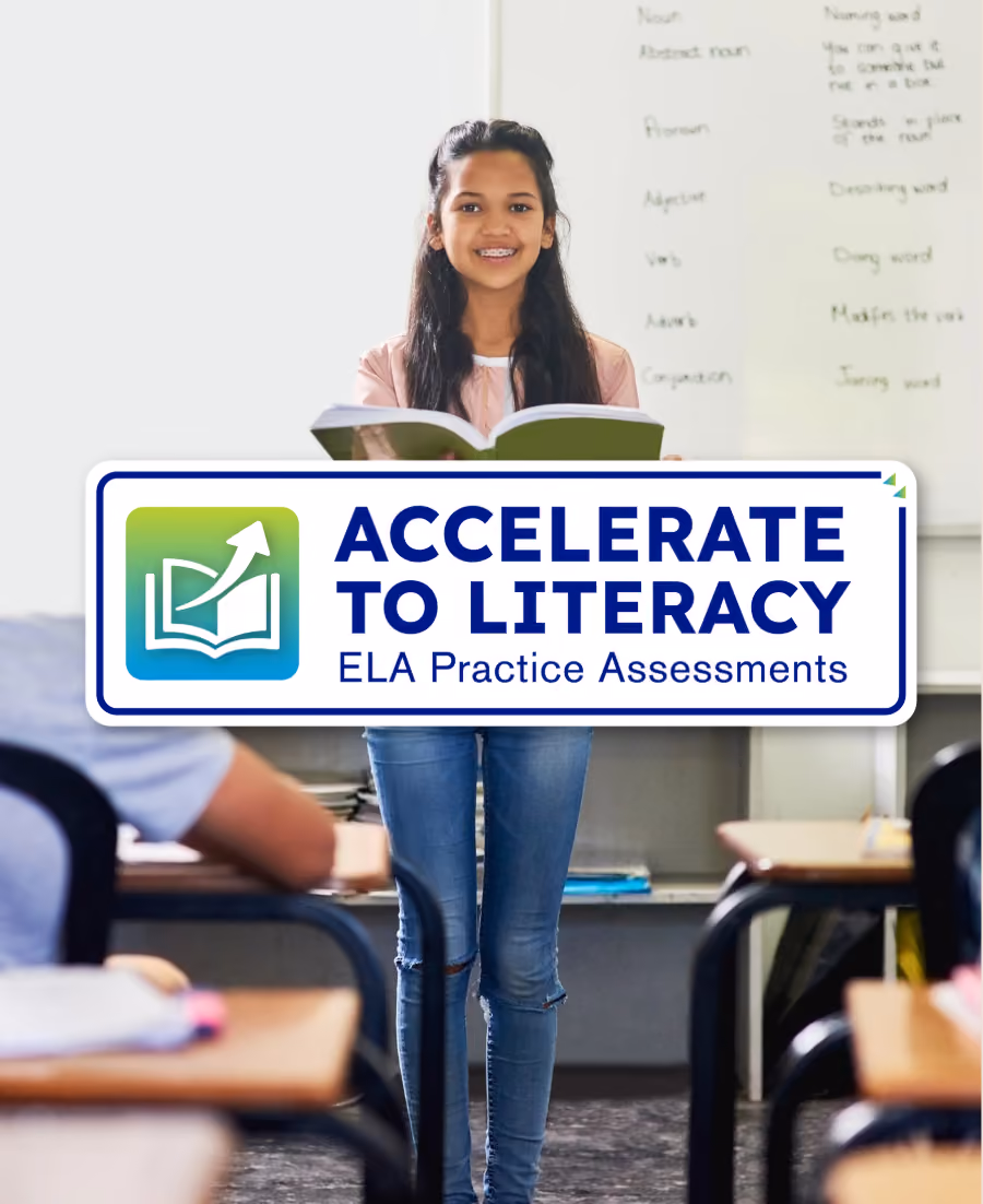 Girl standing in classroom reading from a green book with a whiteboard behind her.