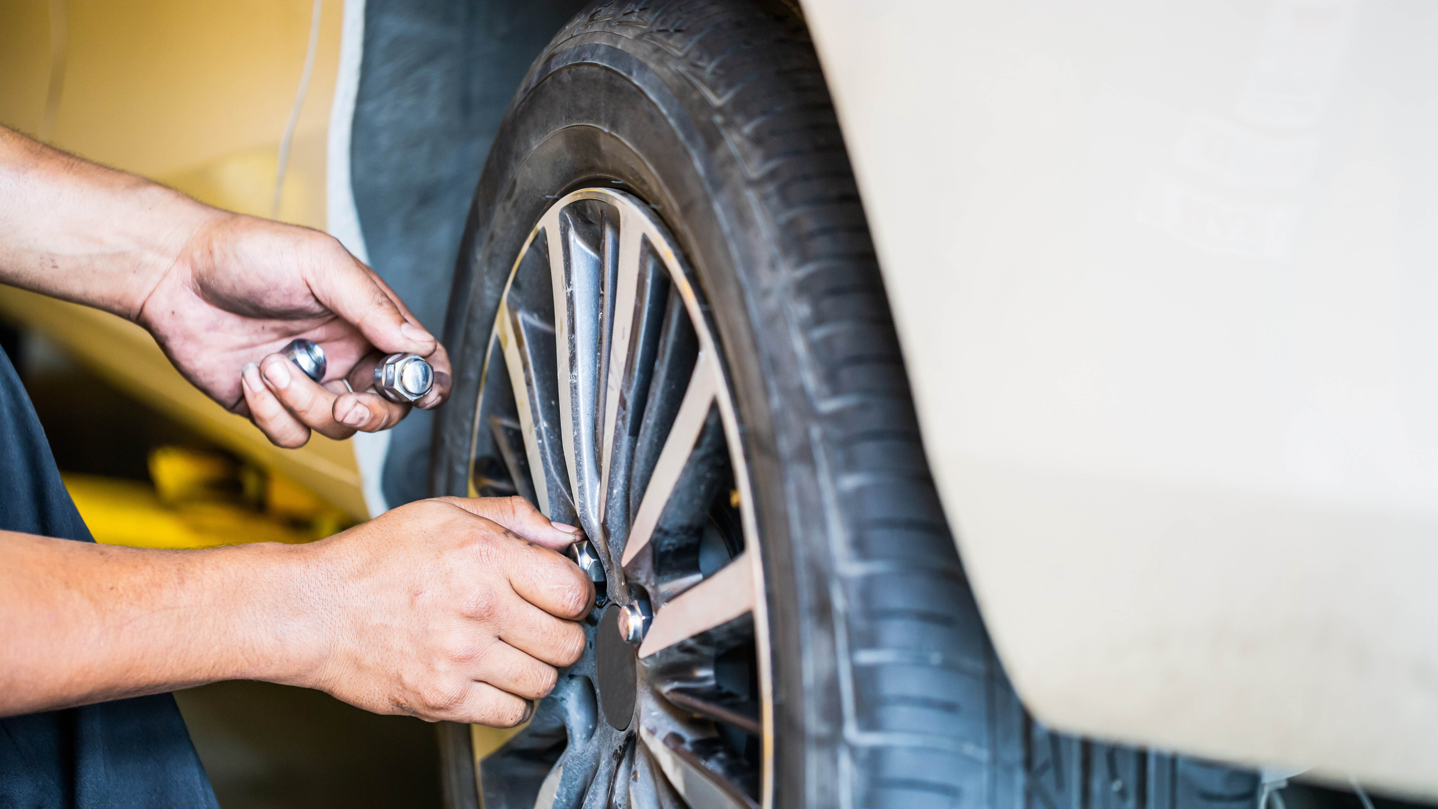 Mechanic loosening wheel lug nuts on a truck in a garage, the hands-on aftermarket work behind SEMA's 2026 Market Report findings