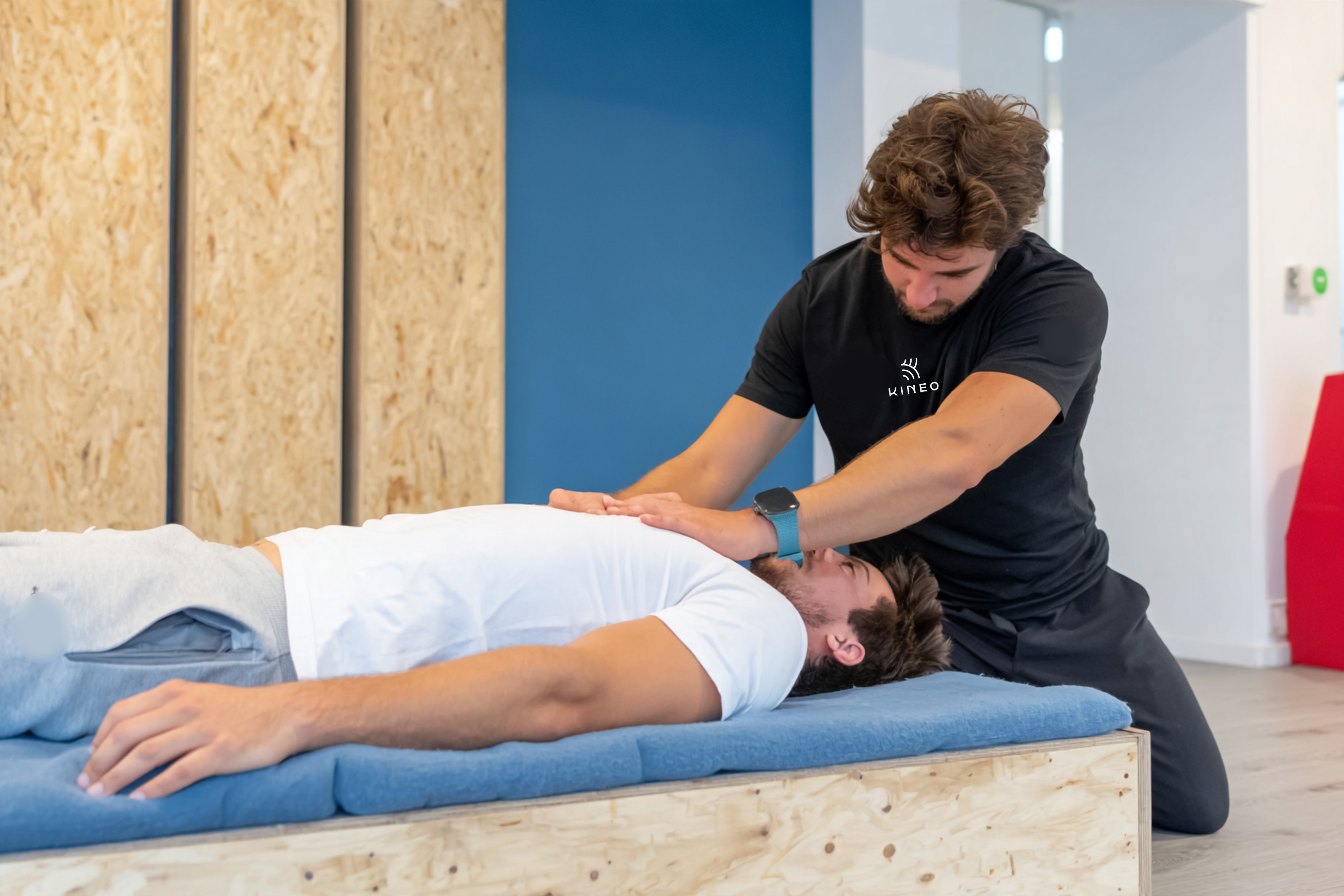 Physiotherapeut testet Hüfte und Leiste eines Fussballspielers auf der Liege