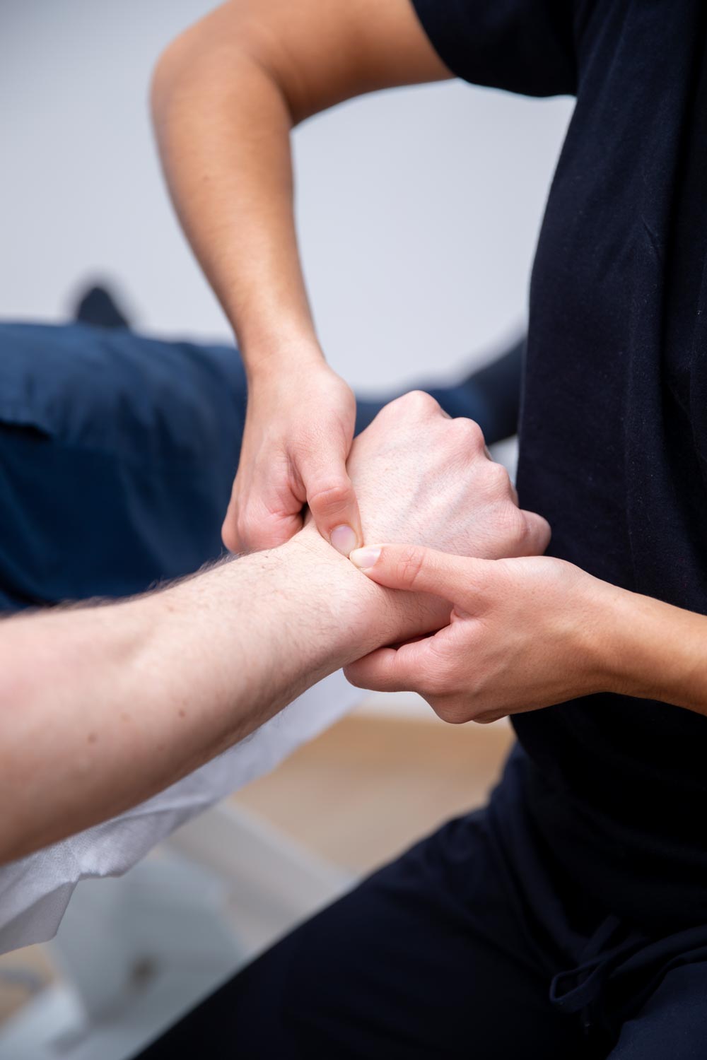Therapeut behandelt die Streckmuskulatur am Unterarm nahe dem Handgelenk