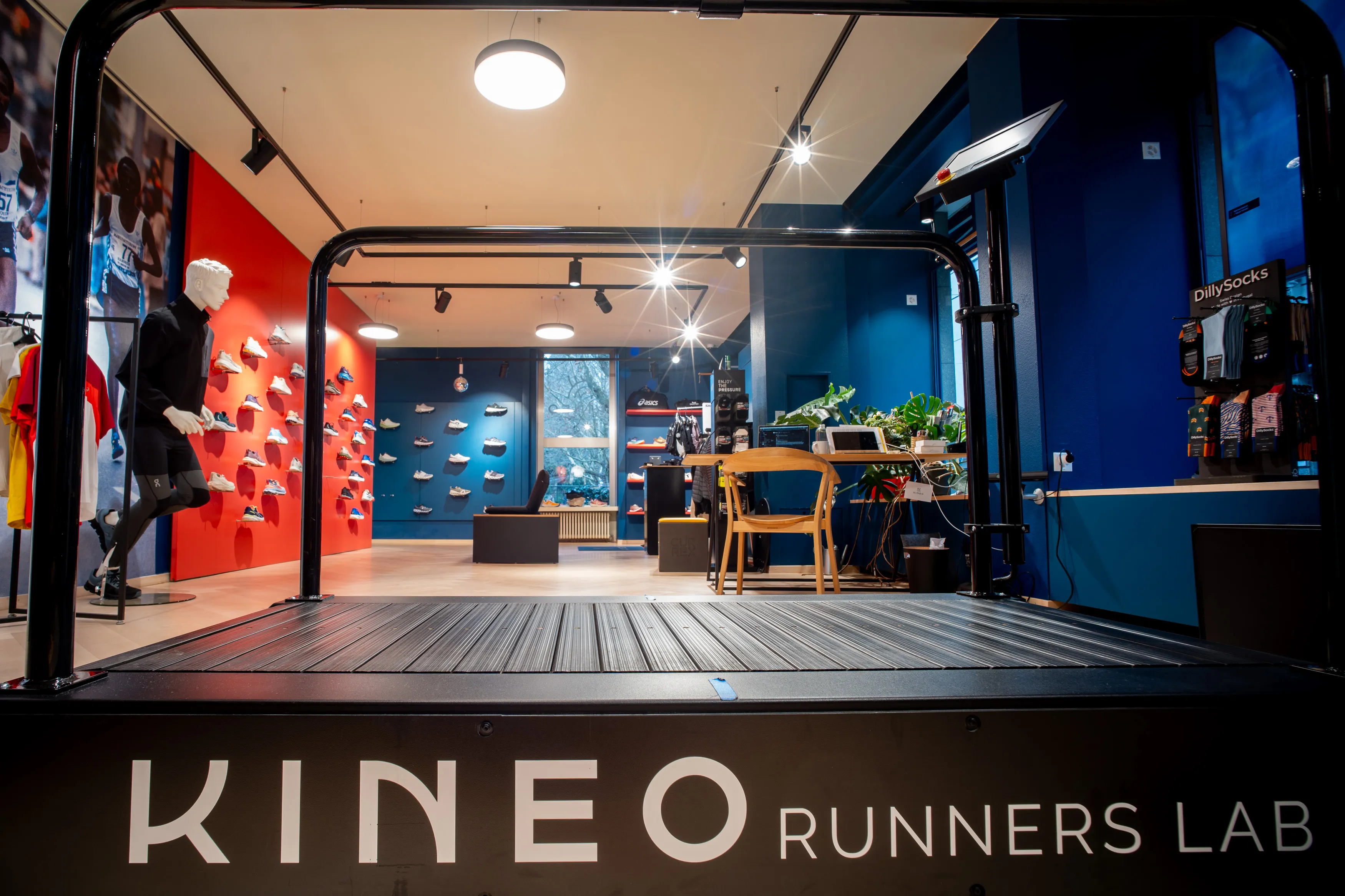 Runners Lab Seefeld ohne Personen mit Laufband und Schriftzug Kineo Runners Lab, dahinter eine Schuhwand im Abendlicht