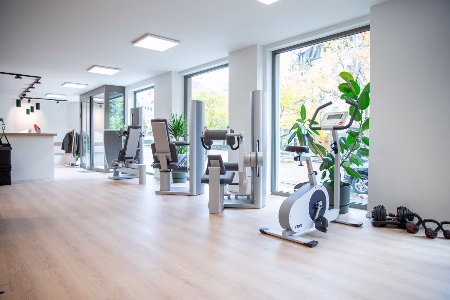 Trainingsfläche bei Kineo Wipkingen mit Kraftgeräten, Velo-Ergometer, Kettlebells und Empfang im Hintergrund