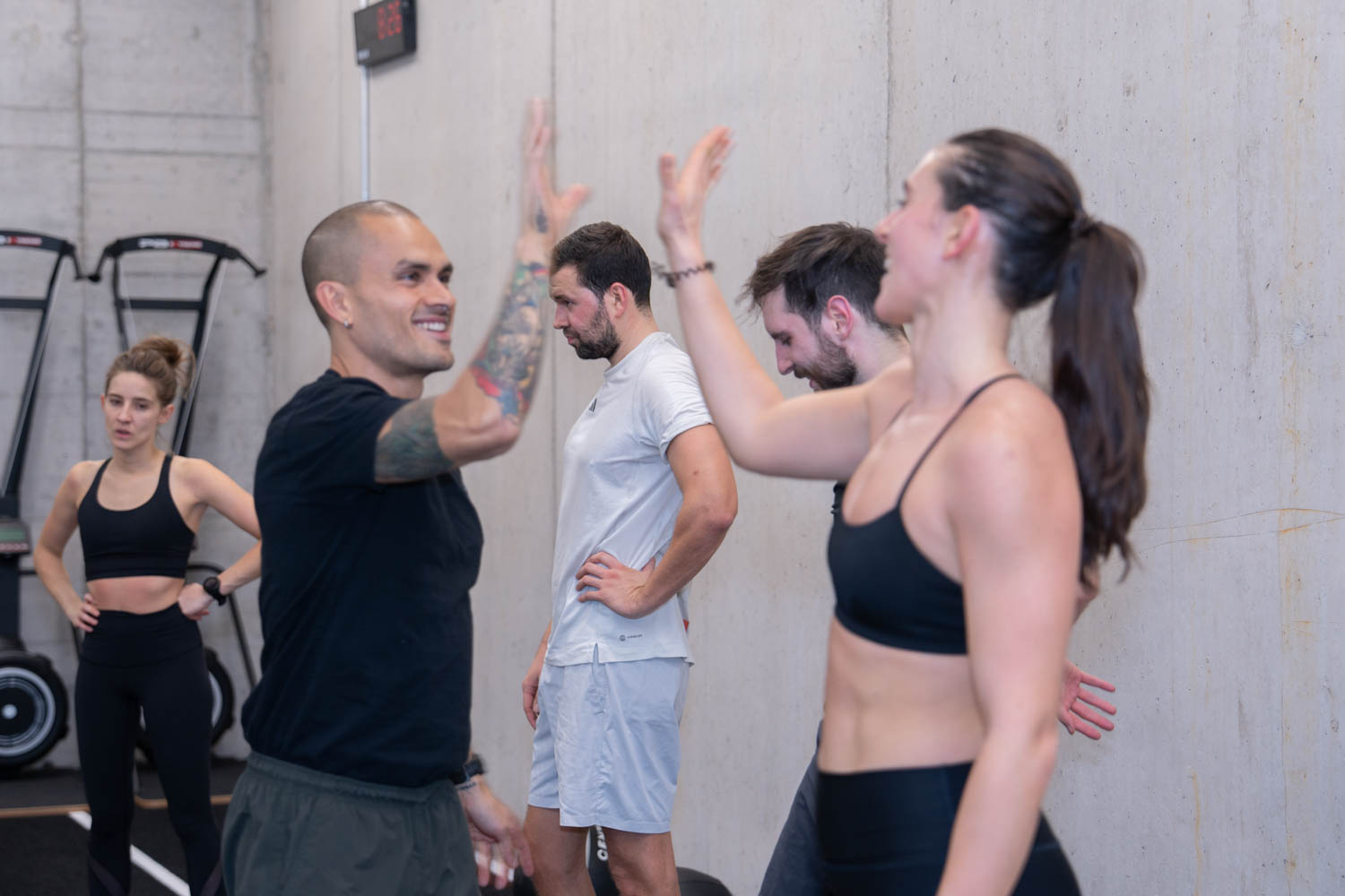 HYROX-Gruppentraining: Coach im schwarzen Shirt gibt ein High-Five, im Hintergrund die Gruppe