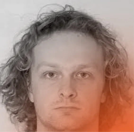 Close-up portrait of a man with medium-length curly hair and a neutral expression.