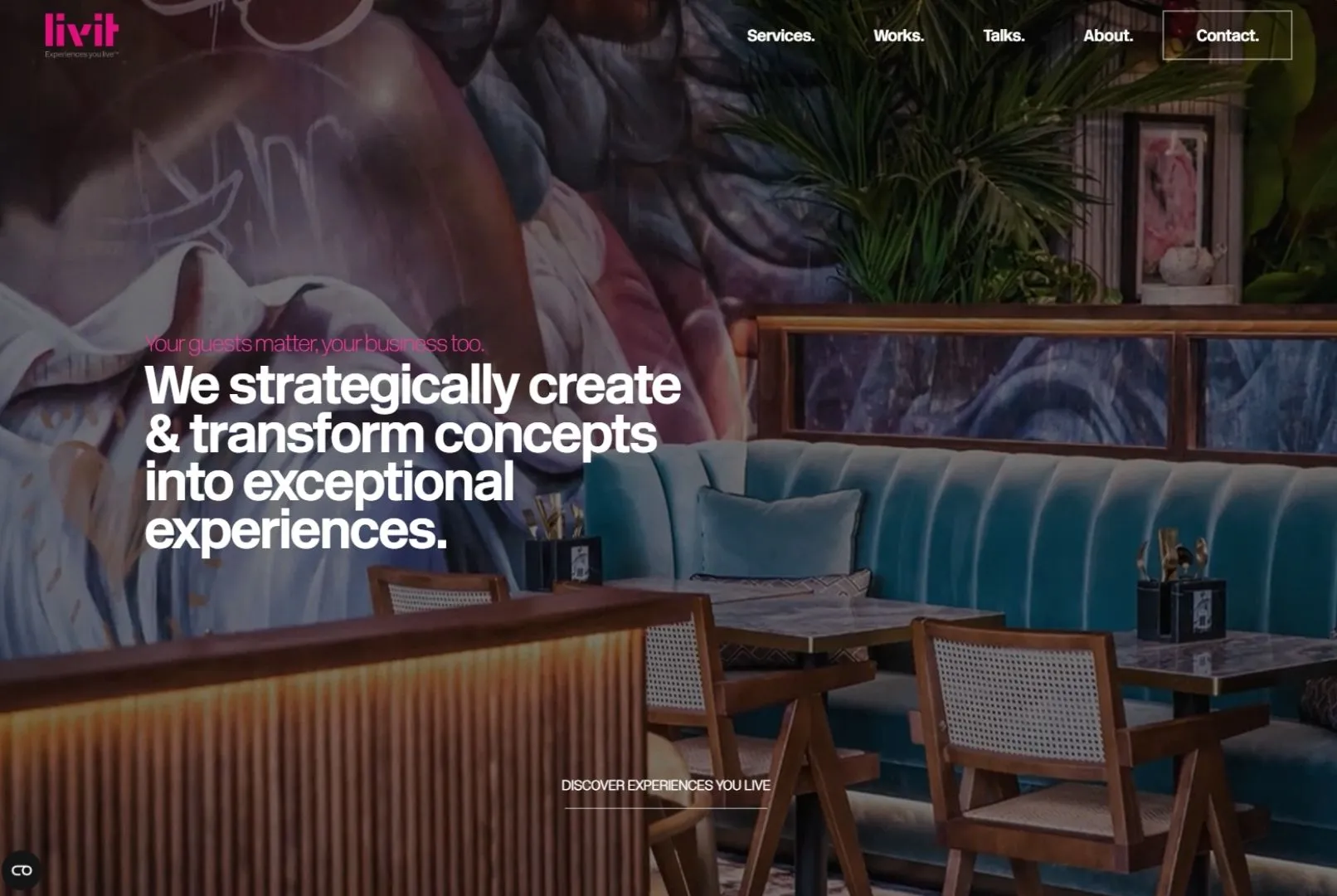 Modern restaurant interior with blue cushioned bench, wooden tables, chairs, and artistic wall mural.