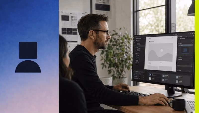 Man wearing glasses using a desktop computer with a web design interface on screen in an office.