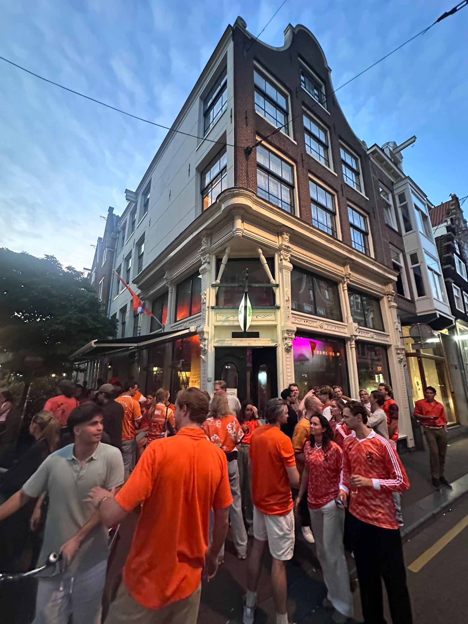The corner building of Café de Huyskamer on Utrechtsestraat with a crowd in orange outside