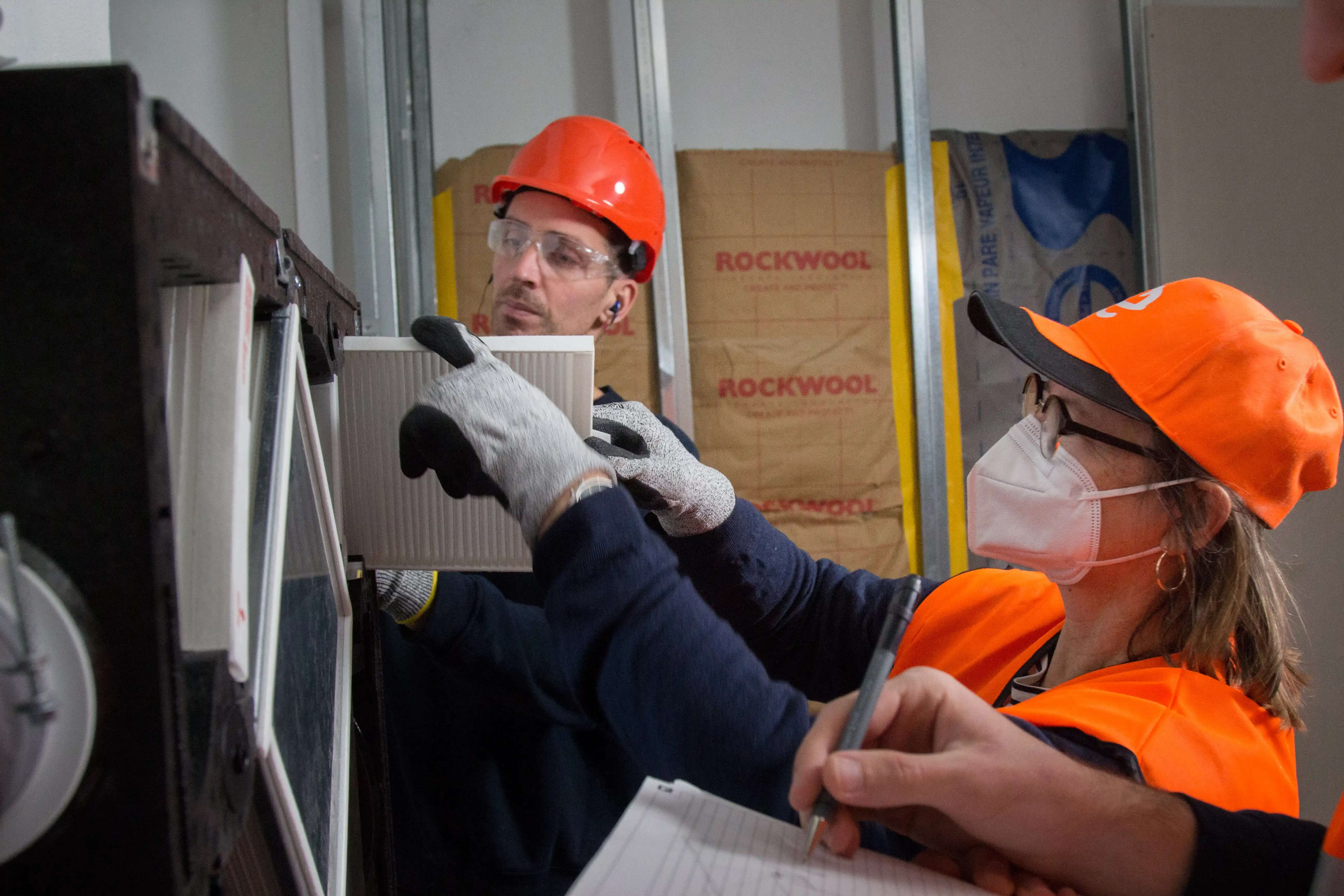 Techniciens installant un filtre à air sur chantier isolé avec Rockwool, en toute sécurité.
