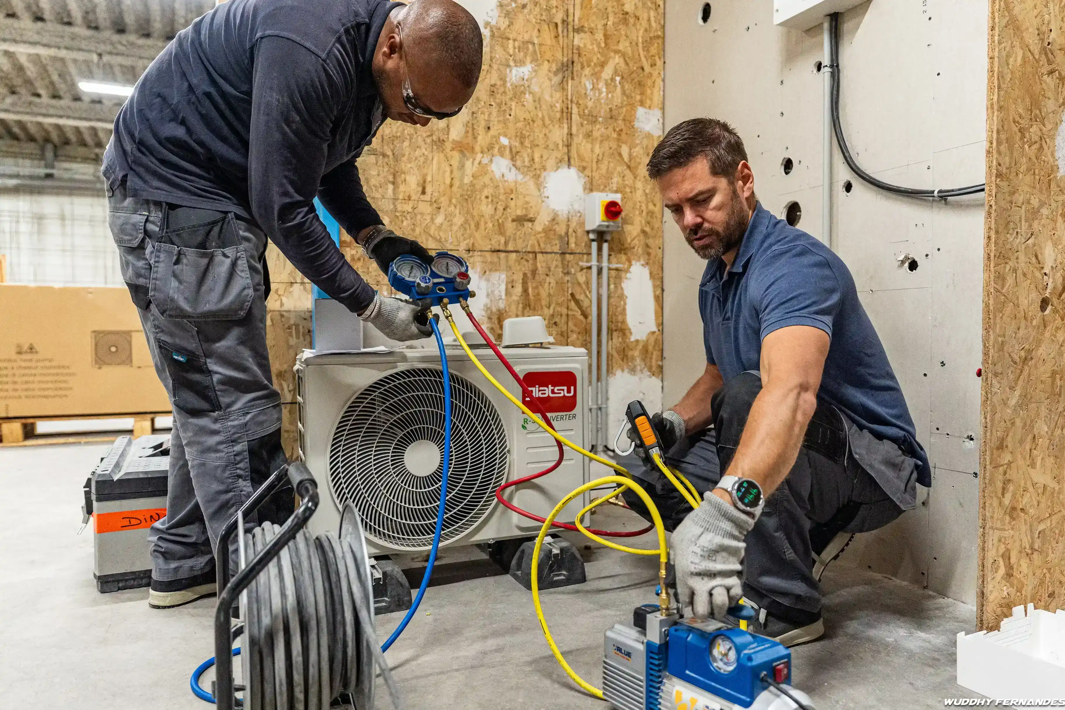 Deux techniciens travaillent sur une pompe à chaleur et l’installation de systèmes de chauffage et de climatisation ans le cadre de la transition énergétique et de la formation aux métiers techniques du bâtiment.