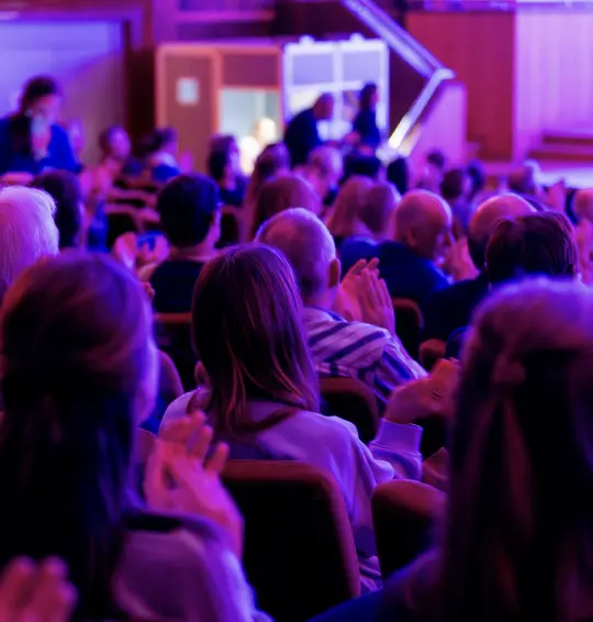 Gevulde congreszaal met roze schijn voor een corporate event