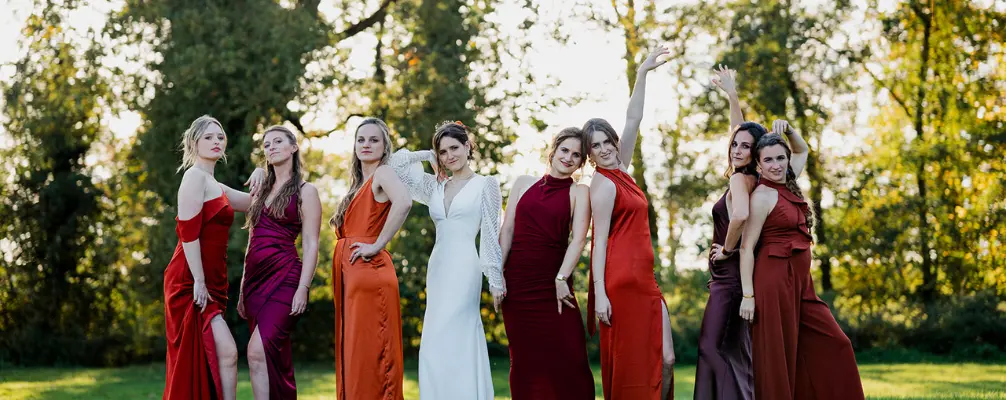 Bruid en bruidsmeisjes poseren in een grasveld tijdens een trouwfeest